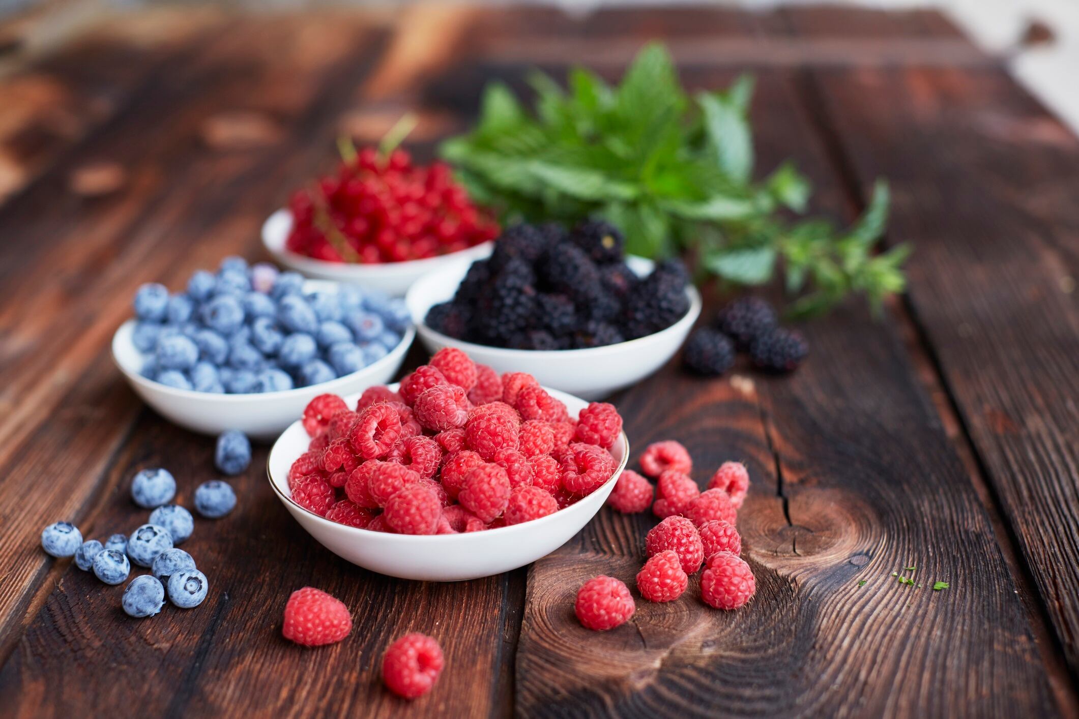 Picnic table with four bowls of fresh berries