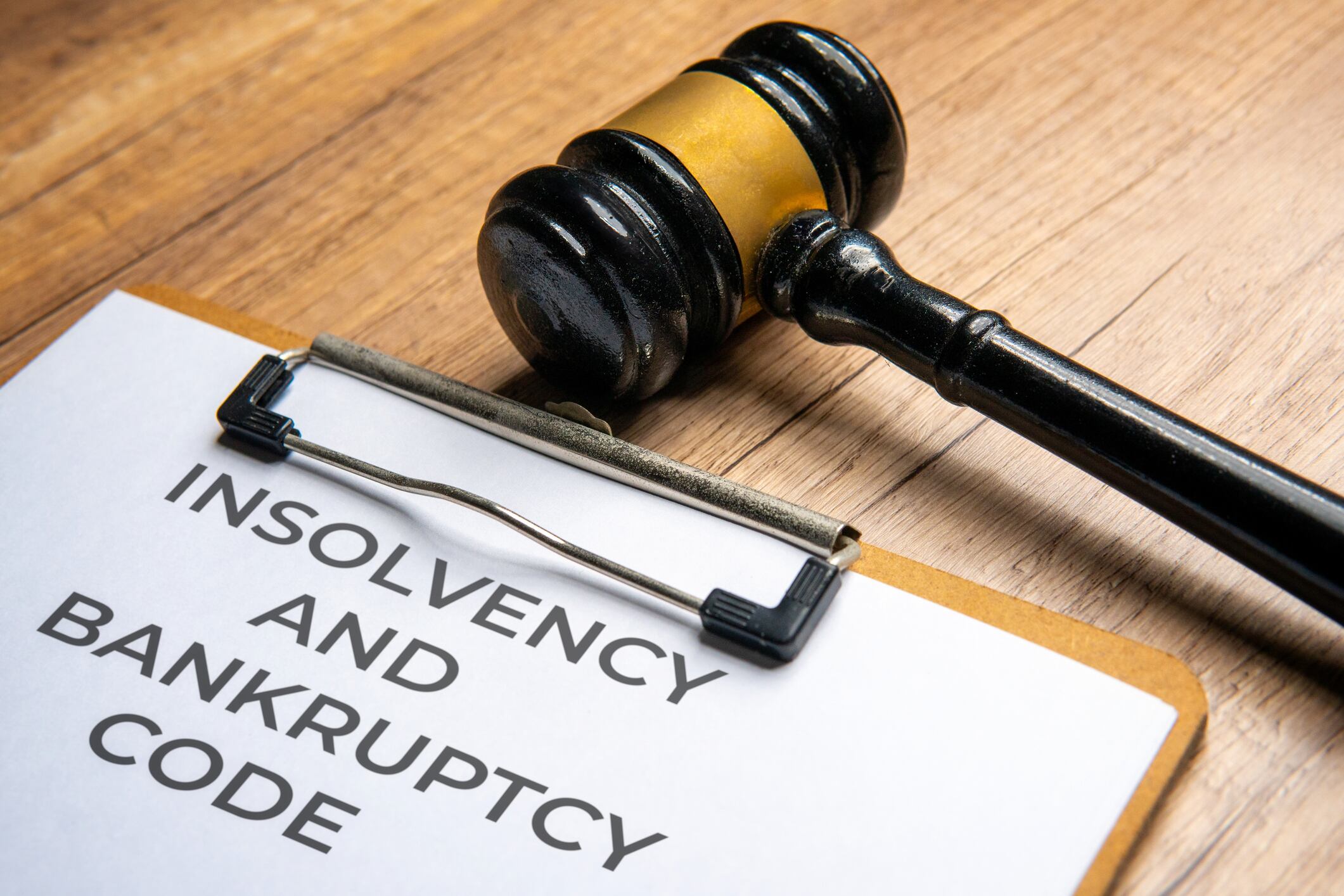 A judge's gavel on a clipboard with a document titled INSOLVENCY AND BANKRUPTCY CODE. Legal action, financial law, and bankruptcy concept.